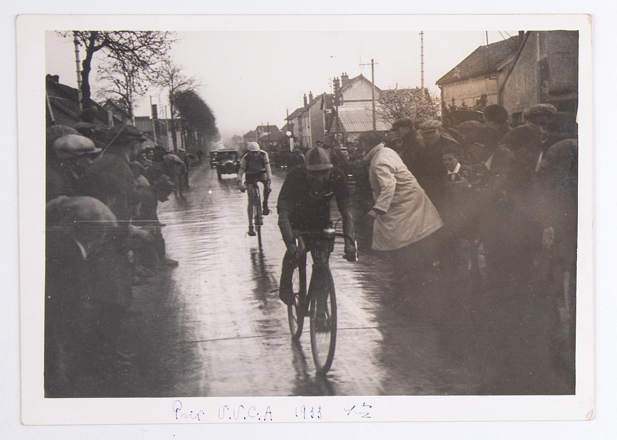 7 mai 1933. Prix de l'Union Vélo Club de l'Aube (U.V.C.A). Deux coureurs cyclistes sous la pluie, au milieu des spectateurs. Lieu non identifié.