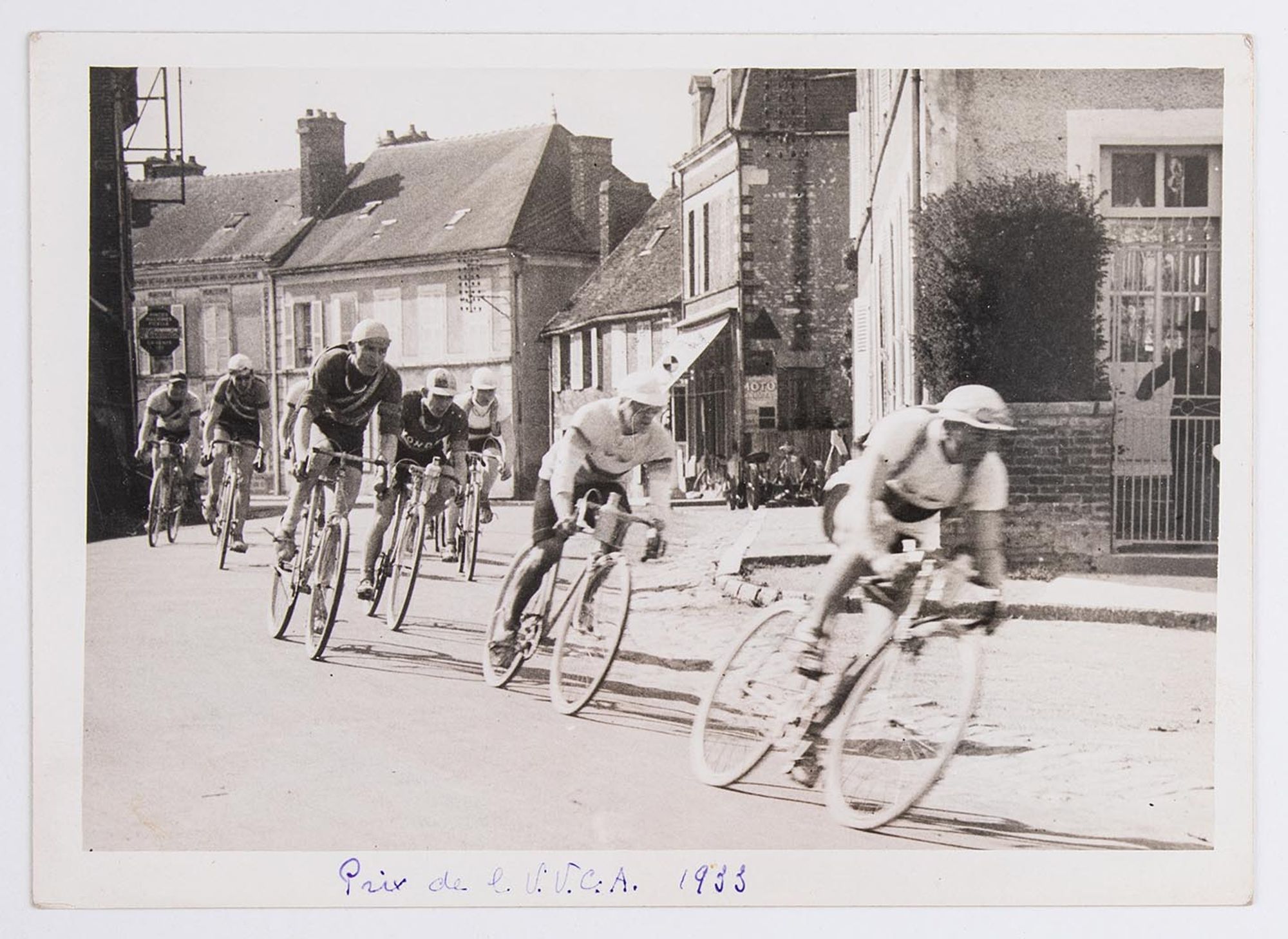 7 mai 1933. Prix de l'Union Vélo Club de l'Aube (U.V.C.A). Un groupe de coureurs cyclistes dans un village. Lieu non identifié.