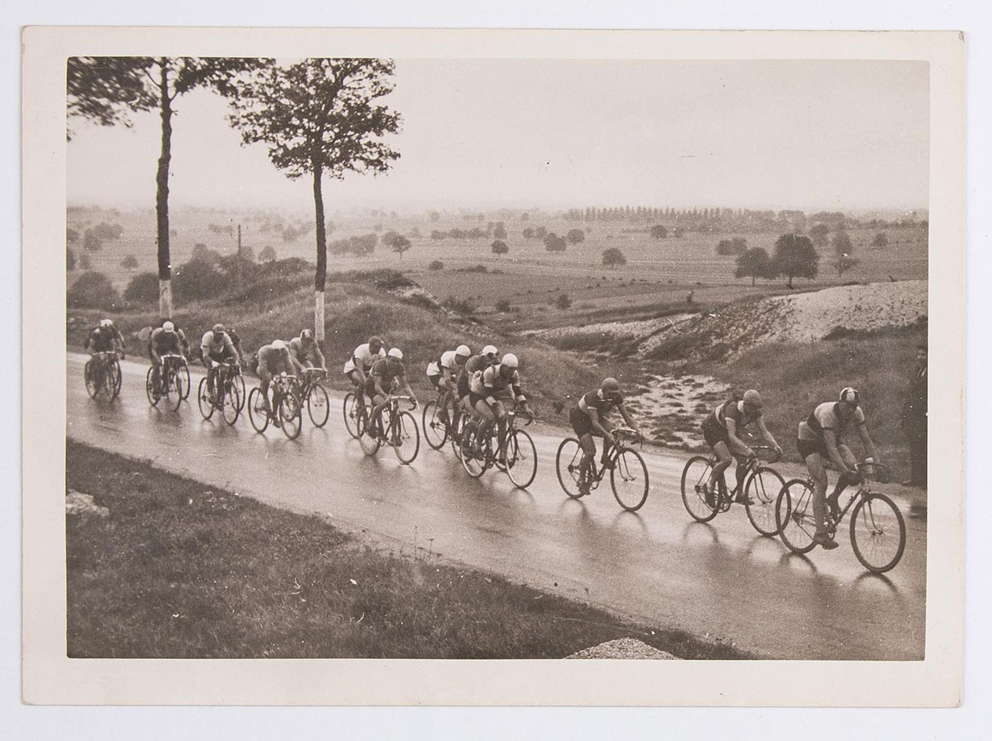 Un groupe de coureurs cyclistes dans la campagne. Course et lieu à identifier.