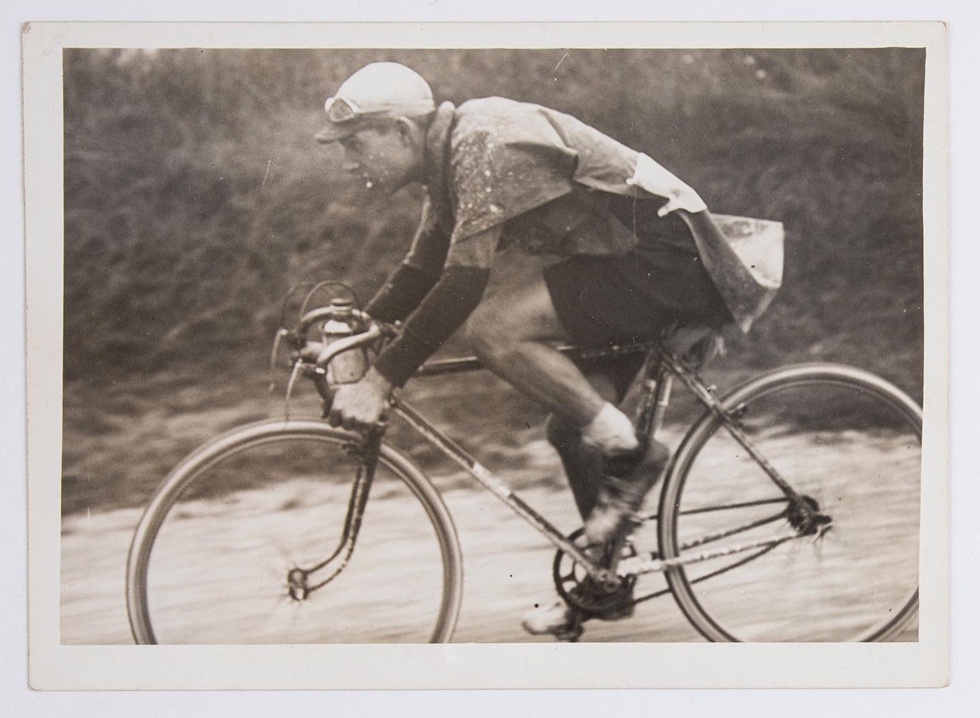 Un coureur cycliste en plein effort, sous une pluie battante. Course et lieu à identifier.