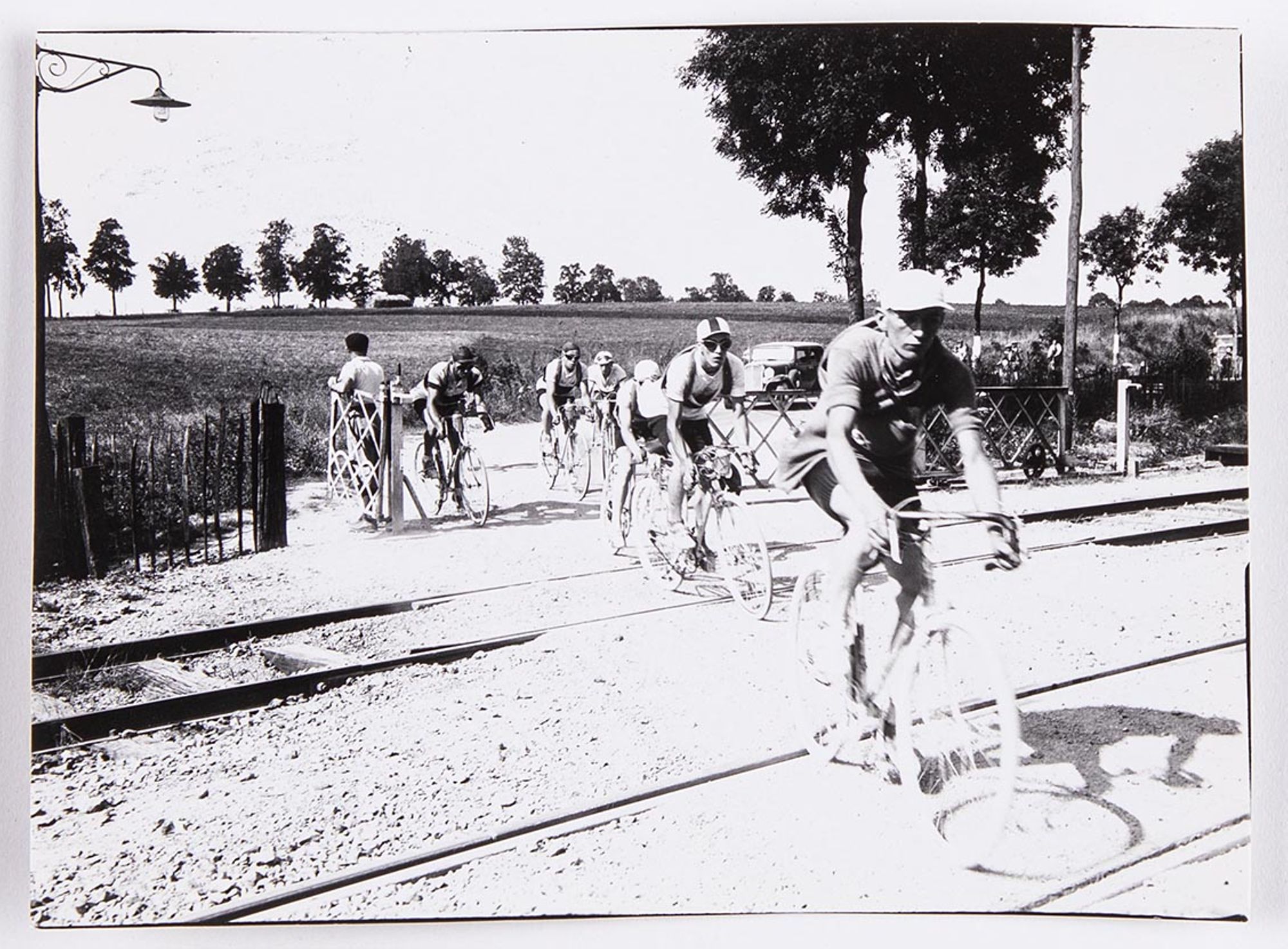 1933. Prix de la Ruche Moderne. Deuxième étape. Passage du peloton, conduit par J. Krubs, sur un passage à niveau. Lieu à identifier.