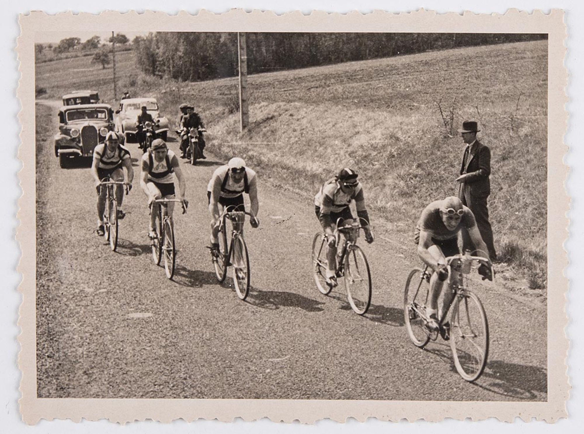 6350. Deuxième vue d'une série de six tirages photographiques représentant une course non identifiée. Focus sur les cinq coureurs à l'arrière du peloton, dans la campagne. Lieu à identifier.