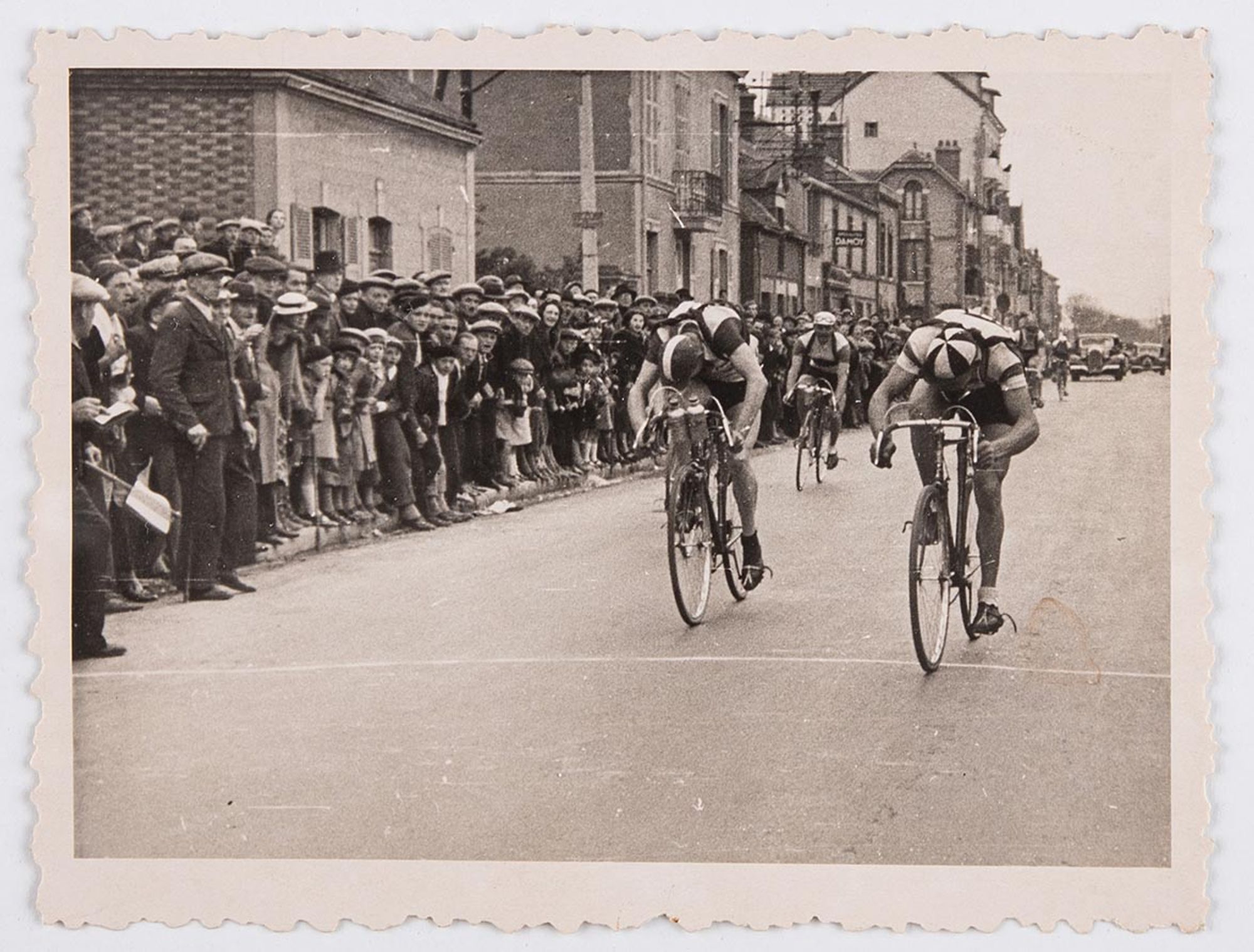 Vue d'une série de six tirages photographiques représentant une course non identifiée. Arrivée des premiers coureurs en ville, au milieu des spectateurs. Lieu à identifier.