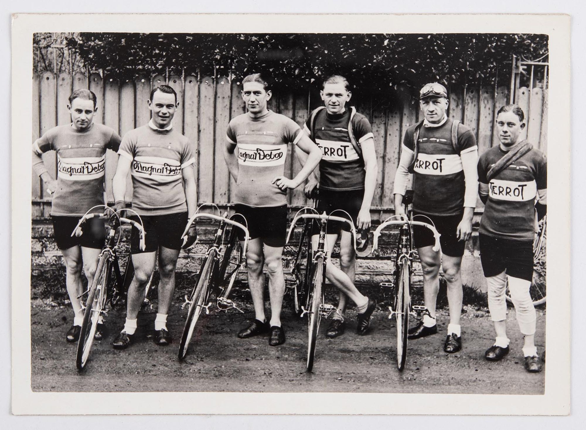 Photographie de groupe. Six coureurs cyclistes, dont J. Krubs (troisième en partant de la gauche), en maillots Magnat-Debon et Terrot posent avec leur vélo. Lieu à identifier.